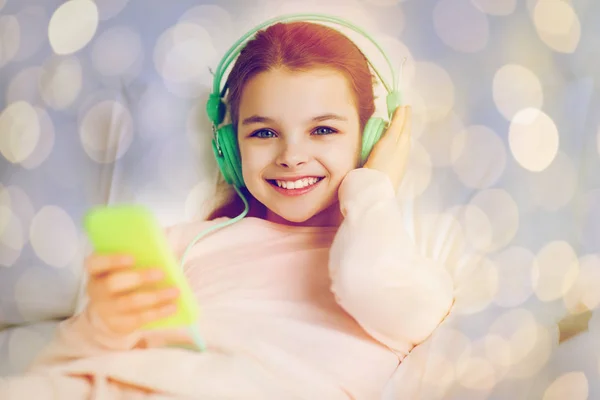 ベッドで音楽を聴くヘッドフォン少女 — ストック写真