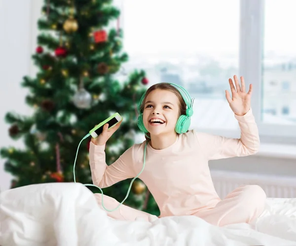 Ragazza con smartphone e cuffie a Natale — Foto Stock