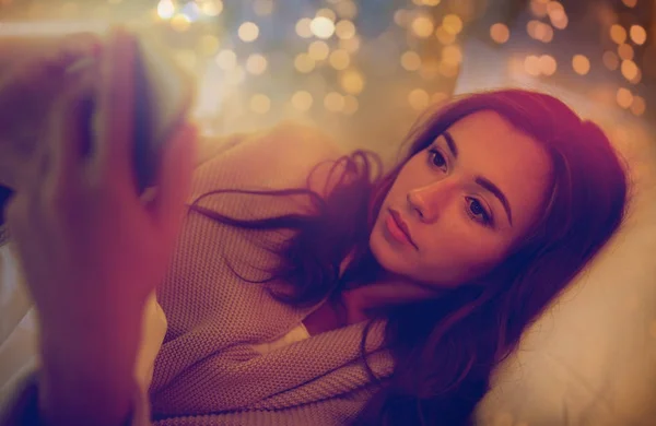自宅の寝室のベッドでスマート フォンを持つ若い女性 — ストック写真