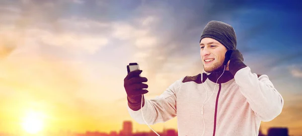 Hombre feliz con auriculares y smartphone en invierno — Foto de Stock