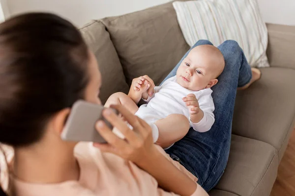 Mãe com bebê chamando no smartphone em casa — Fotografia de Stock