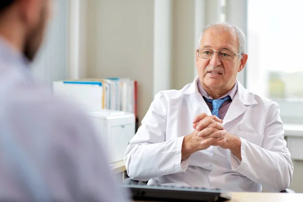 Senior doctor talking to male patient at hospital — Stock Photo, Image