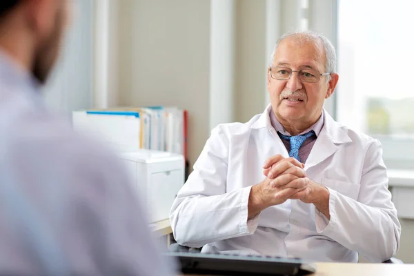 Médico sênior falando com paciente do sexo masculino no hospital — Fotografia de Stock