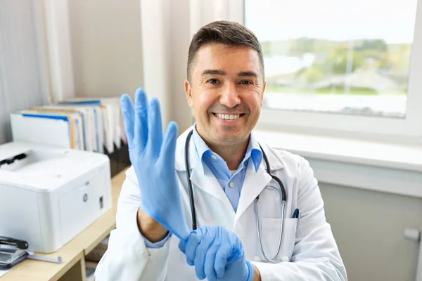 Médico sorridente com luvas de proteção na clínica — Fotografia de Stock