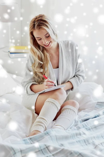 Feliz joven con cuaderno en la cama en casa Imagen De Stock