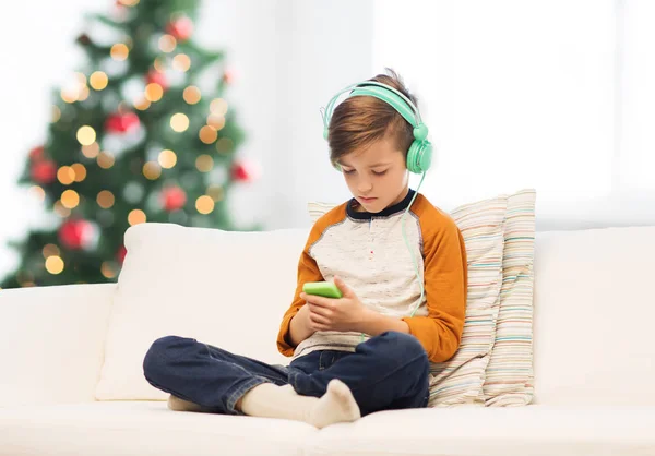 Menino com smartphone e fones de ouvido no Natal — Fotografia de Stock
