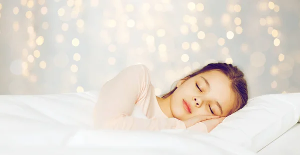 Chica durmiendo en la cama durante las vacaciones luces —  Fotos de Stock