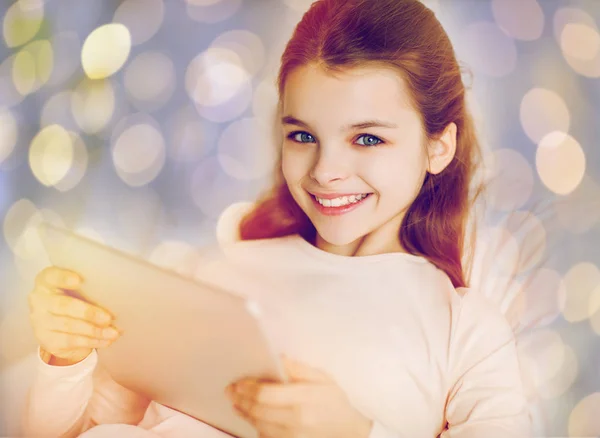 Happy girl in bed with tablet pc over lights — Stock Photo, Image