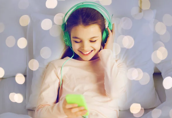 Menina com fones de ouvido ouvir música na cama — Fotografia de Stock