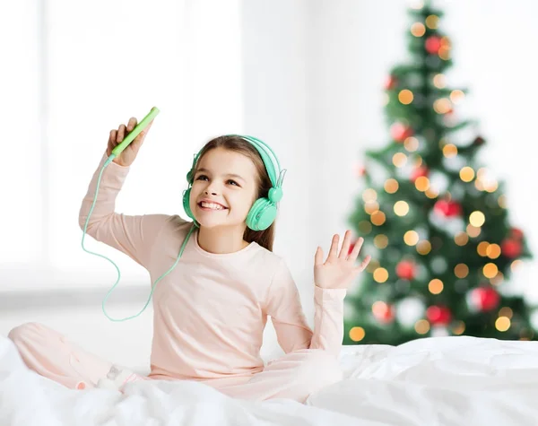 Fille avec smartphone et écouteurs à Noël — Photo