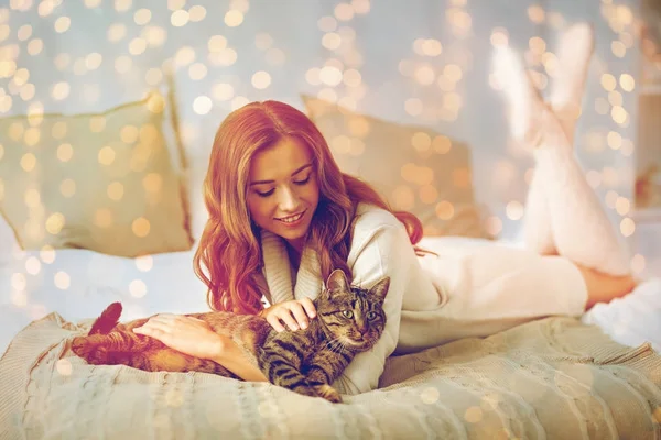 Jovem feliz com gato deitado na cama em casa — Fotografia de Stock