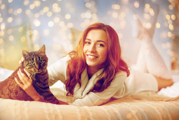 Jovem feliz com gato deitado na cama em casa — Fotografia de Stock