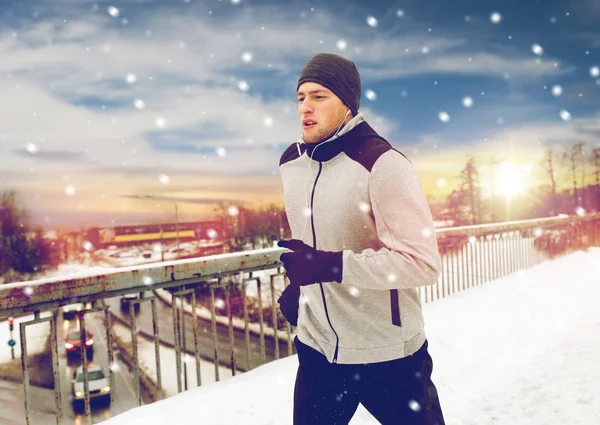 Man in oortelefoons loopt langs winter brug — Stockfoto