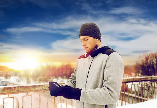 Mannen i hörlurar med smartphone på vintern bro — Stockfoto