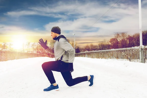 Mann trainiert und macht Kniebeugen auf Winterbrücke — Stockfoto