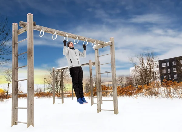 Young man exercising on horizontal bar in winter — Stock Photo, Image