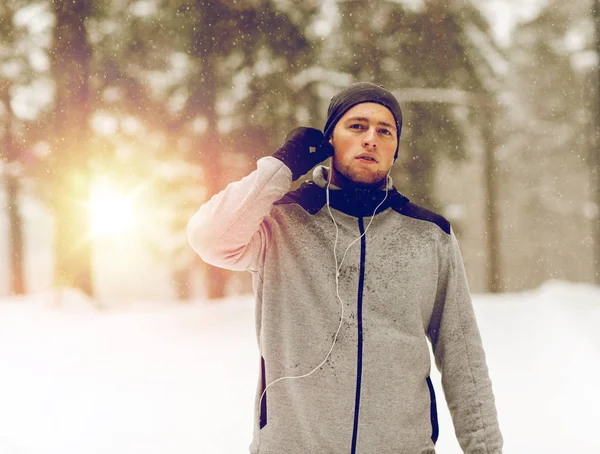 Sport man med hörlurar i vinter skog — Stockfoto