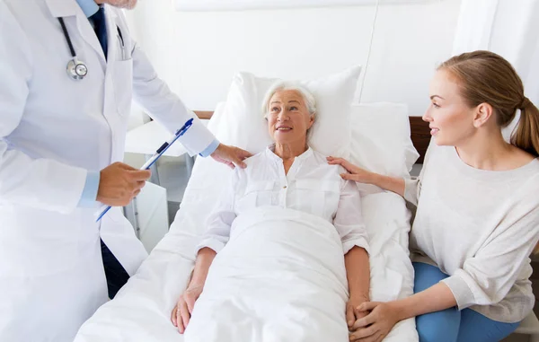 Starší žena a lékař se schránkou v nemocnici — Stock fotografie
