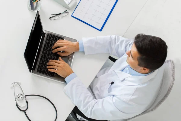 Arzt mit Kardiogramm und Laptop in Klinik — Stockfoto