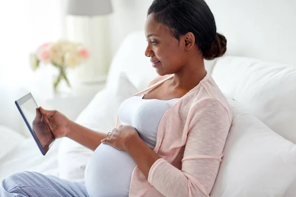 Glückliche Schwangere mit Tablet-PC zu Hause — Stockfoto