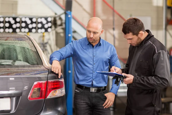 Mechanic and customer looking at car taillight — Stock Photo, Image