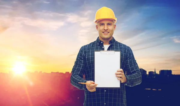 Construtor masculino em chapéu duro amarelo com prancheta — Fotografia de Stock