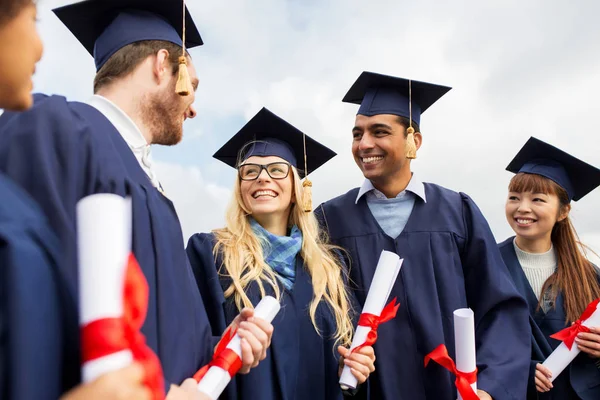 Estudantes felizes em placas de argamassa com diplomas — Fotografia de Stock