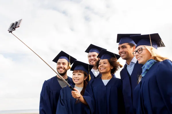 Grupo de estudantes felizes ou graduados que tomam selfie — Fotografia de Stock