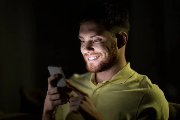 Jovem feliz com smartphone à noite — Fotografia de Stock