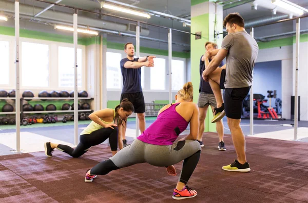Grupp av glada vänner stretching i gymmet — Stockfoto