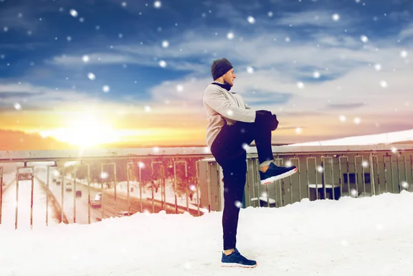 Mann trainiert und streckt Bein auf Winterbrücke — Stockfoto
