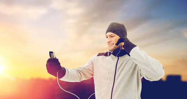 Glücklicher Mann mit Kopfhörer und Smartphone im Winter — Stockfoto