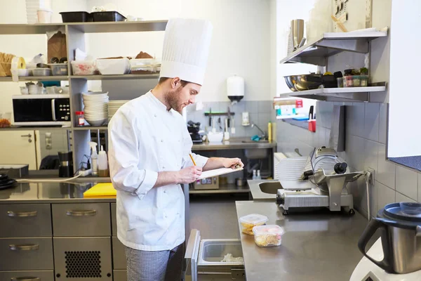 Chef con portapapeles haciendo inventario en la cocina — Foto de Stock