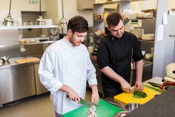 Cocinero y cocinar comida en la cocina del restaurante — Foto de Stock