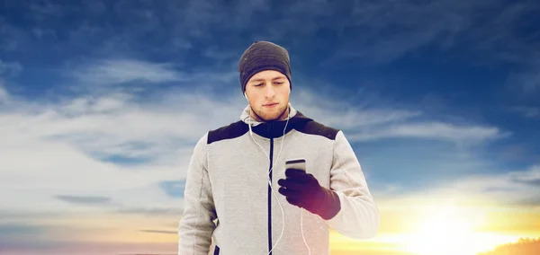 Happy man with earphones and smartphone in winter Stock Photo