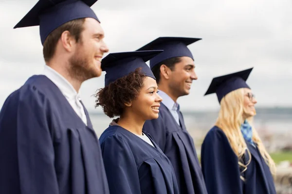 Happy students or bachelors in mortar boards — Stock Photo, Image