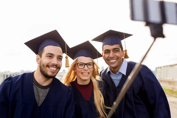 Estudiantes felices o graduados tomando selfie al aire libre — Foto de Stock