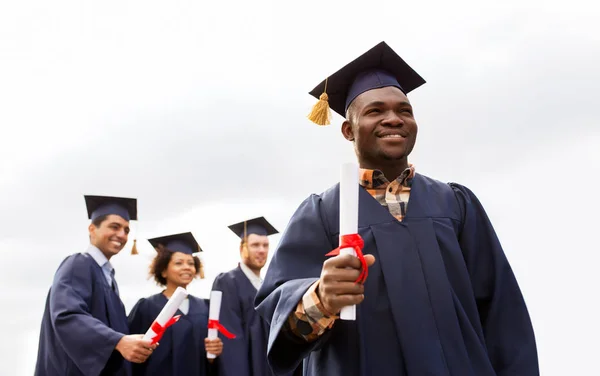 Gelukkige studenten in mortierplanken met diploma 's — Stockfoto