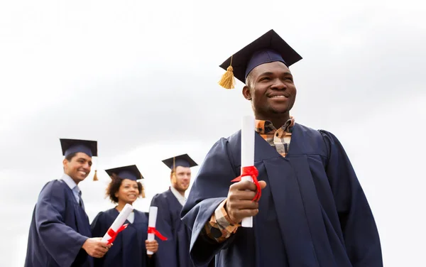 Estudiantes felices en morteros con diplomas —  Fotos de Stock