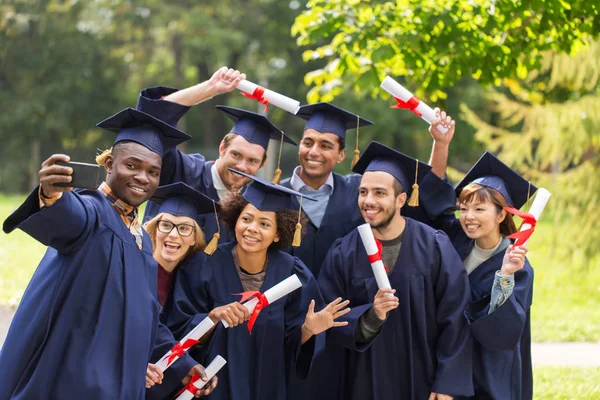 Students or graduates with diplomas taking selfie — Stock Photo, Image