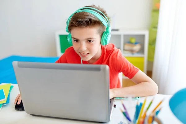 Jongen in hoofdtelefoon spelen video game op laptop — Stockfoto