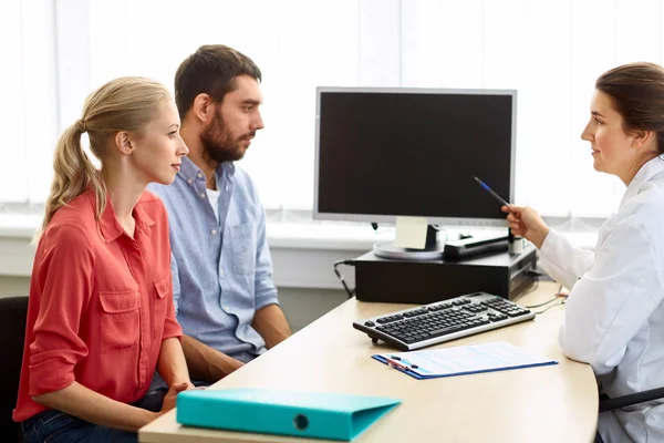 Paar und Arzt zeigen auf Computer in Klinik — Stockfoto