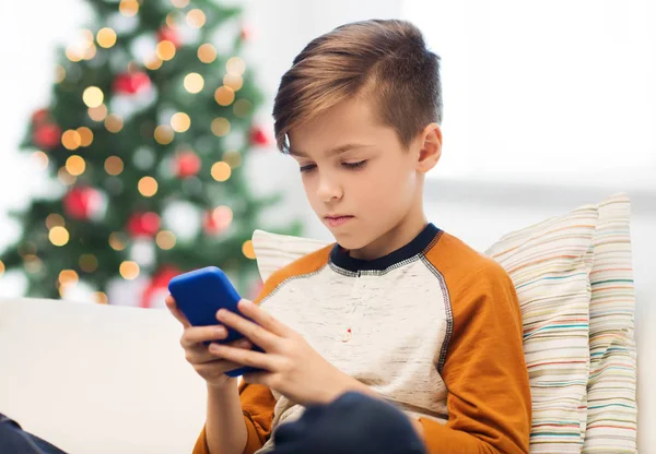 Мальчик со смартфоном дома на Рождество — стоковое фото