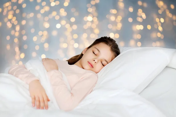 Chica durmiendo en la cama durante las vacaciones luces —  Fotos de Stock