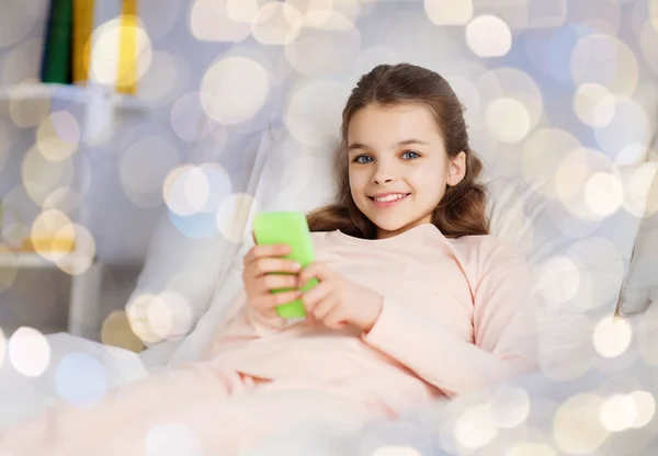 Glückliches Mädchen zu Hause mit Smartphone im Bett liegend — Stockfoto