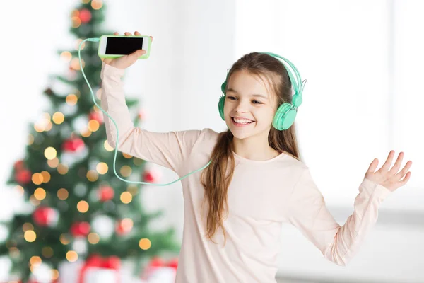 Chica con smartphone y auriculares en Navidad —  Fotos de Stock