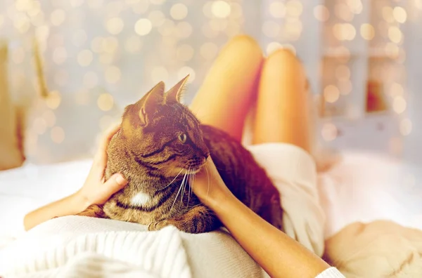 Νεαρή γυναίκα με γάτα ξαπλωμένη στο κρεβάτι στο σπίτι — Φωτογραφία Αρχείου