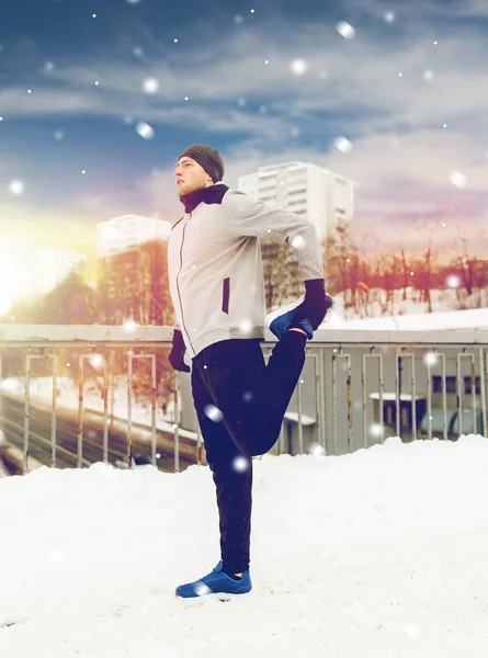 Mann trainiert und streckt Bein auf Winterbrücke — Stockfoto