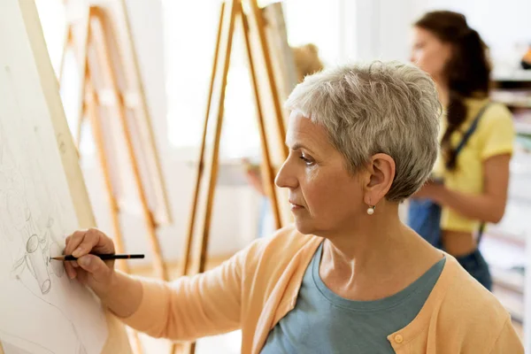 Старша жінка малює на мольберті в студії мистецтв — стокове фото