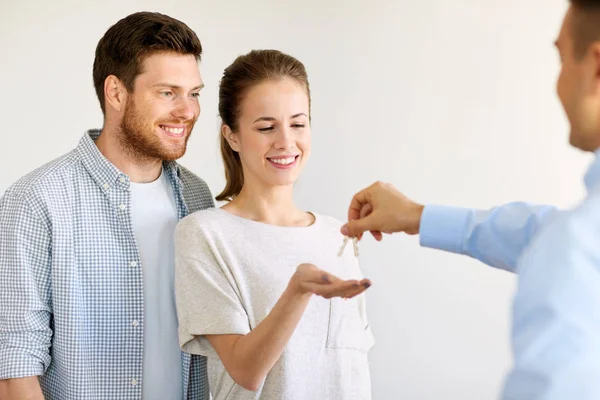 Agente immobiliare dando le chiavi dalla nuova casa alla coppia felice — Foto Stock